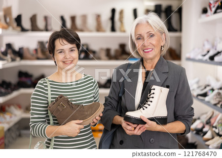 Adult and elderly women choosing boots in store Adult and elderly women choosing boots in store 121768470