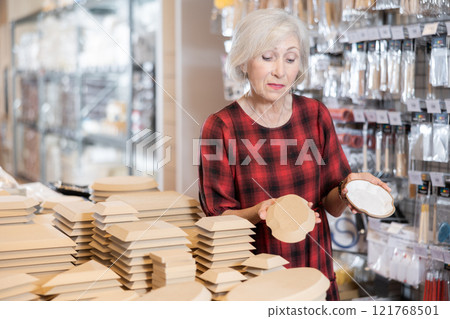 Elderly female customer chooses various wooden molds for future clay molding Elderly female customer chooses various wooden molds for future clay molding 121768501