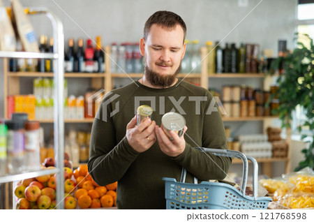 man chooses canned food. 121768598