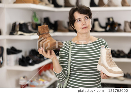 Woman takes samples from showcase and examines shoes Woman takes samples from showcase and examines shoes 121768600