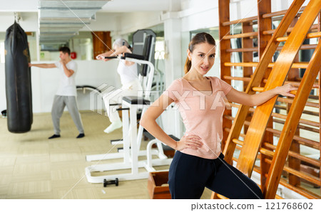 Woman standing at ladder in gym and looking at camera Woman standing at ladder in gym and looking at camera 121768602