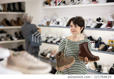 Woman takes samples from showcase and examines shoes 121768610