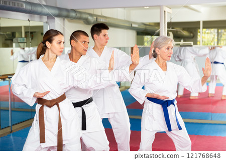 Karate or taekwondo training - athletes in kimono stand in fighting stance Karate or taekwondo training - athletes in kimono stand in fighting stance 121768648