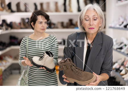Adult and elderly women choosing boots in store 121768649