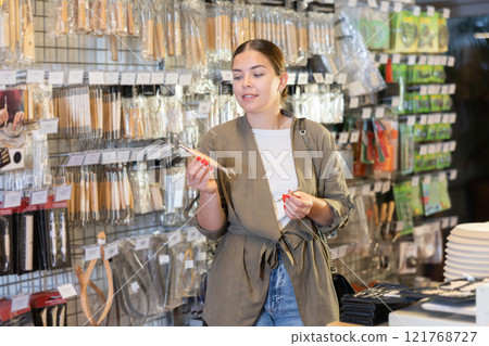 Young woman chooses a set of tools for working with clay in specialized store Young woman chooses a set of tools for working with clay in specialized store 121768727