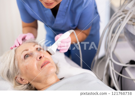 Old woman having face laser therapy procedure 121768738