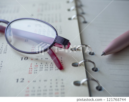 Calendar, notebook and glasses placed on the table 121768744