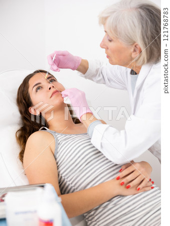 Young woman having mesotherapy procedure on her face performed by dermatologist 121768783
