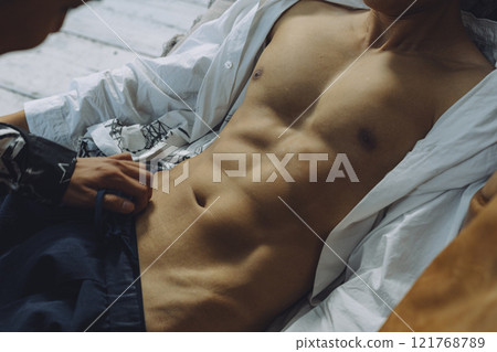 Muscular man bed scene 121768789