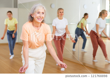 Elderly woman dancing jazz during group training 121768898
