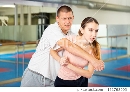 Active girl conducts painful grip on self-defense training in gym 121768903