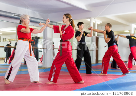 Elderly woman sparring with girl during martial arts training Elderly woman sparring with girl during martial arts training 121768908