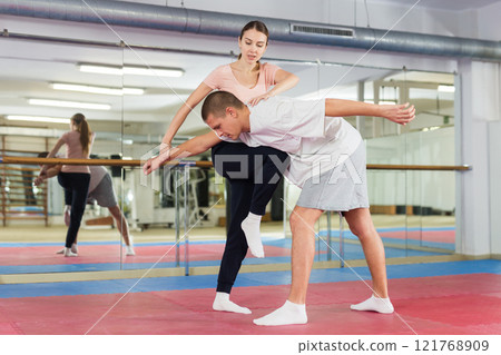 Girl practicing knee kick with arm hold to man in self defence training Girl practicing knee kick with arm hold to man in self defence training 121768909