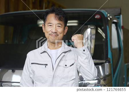 A male worker pumping his fist in front of a truck A male worker pumping his fist in front of a truck 121769855