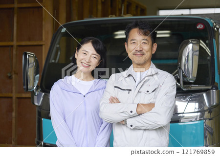 Portrait of a worker couple standing in front of a truck, looking at the camera Portrait of a worker couple standing in front of a truck, looking at the camera 121769859