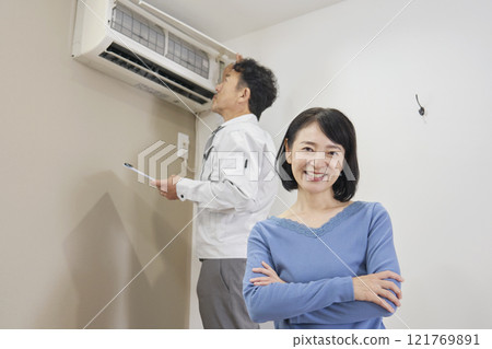 A woman feels relieved after repairing a broken air conditioner 121769891