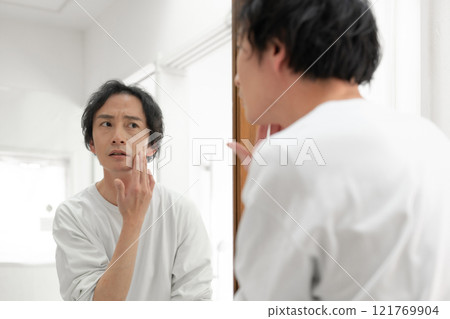 A man worried in front of a mirror 121769904