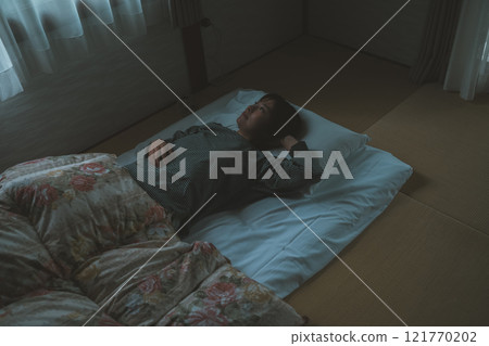 一名婦女因窗外的光線而在清晨醒來 121770202