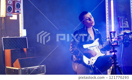 Punk rock musician hosting a live event concert on online streaming session, singing heavy metal alternative music in the studio. Artist doing a digital performance on social media. Camera A. Punk rock musician hosting a live event concert on online streaming session, singing heavy metal alternative music in the studio. Artist doing a digital performance on social media. Camera A. 121770293