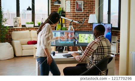 Creative interracial couple collaborating on video editing process, discussing multiple ways to use the professional software and color wheel. Diverse multiethnic man and woman at home. Camera A. 121770296