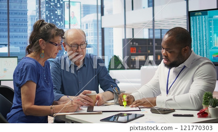 Senior people consulting with their financial banker about retirement plans, focusing on securing their financial future. Receiving professional advice for income and pension. Camera B. Senior people consulting with their financial banker about retirement plans, focusing on securing their financial future. Receiving professional advice for income and pension. Camera B. 121770303