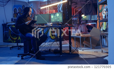 Man arriving in underground bunker, using it to mask his location while committing international espionage. Spy using tablet and computer systems to steal governmental secrets 121770305