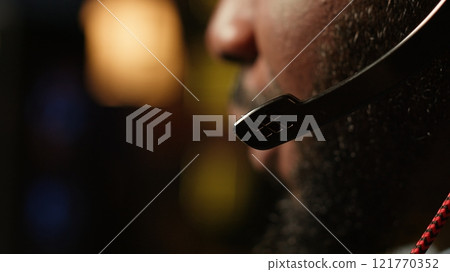 Man having fun playing videogames on PC while chatting with teammates through headphones mic. Close up of gamer battling rival players, communicating with friends through headset microphone, camera A 121770352