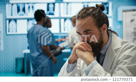 Worried doctor feeling tired and struggling with analytics for a diagnosis, overworked medic under pressure in private facility. Physician expert trying to provide treatment. Camera B. 121770371