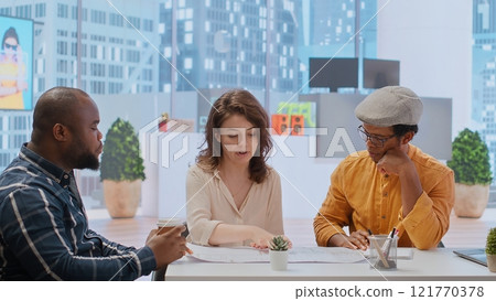 Entrepreneur and real estate agent evaluate investment opportunities by studying blueprints, planning a new high class office layout. Business people meeting realtor financier. Camera B. Entrepreneur and real estate agent evaluate investment opportunities by studying blueprints, planning a new high class office layout. Business people meeting realtor financier. Camera B. 121770378