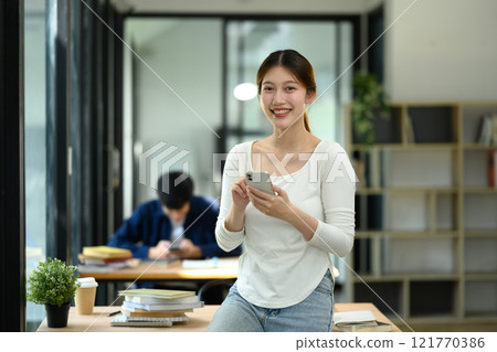 Smiling female employee using mobile phone in modern office Smiling female employee using mobile phone in modern office 121770386