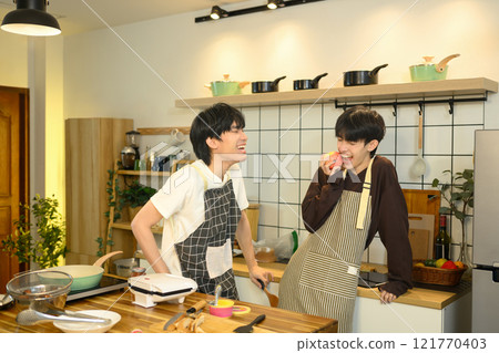 Joyful gay couple sharing a lighthearted moment in the kitchen while preparing food together. Joyful gay couple sharing a lighthearted moment in the kitchen while preparing food together. 121770403