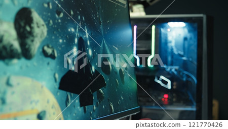 Man at home using high end computer system to play demanding science fiction videogame. Gamer enjoying high quality game, streaming it online, shooting laser beams with spaceship, camera B close up 121770426