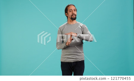 Portrait of assertive man asking for timeout, doing hand gestures, feeling fatigued. Unhappy person doing vehement pause sign gesturing, wishing for break, studio background, camera A Portrait of assertive man asking for timeout, doing hand gestures, feeling fatigued. Unhappy person doing vehement pause sign gesturing, wishing for break, studio background, camera A 121770455
