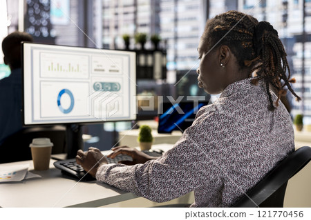 Businesswoman analyzing performance metrics on her computer at the workplace, office life. Engaged in strategic planning, she reviews data to support company objectives for successful outcomes. Businesswoman analyzing performance metrics on her computer at the workplace, office life. Engaged in strategic planning, she reviews data to support company objectives for successful outcomes. 121770456