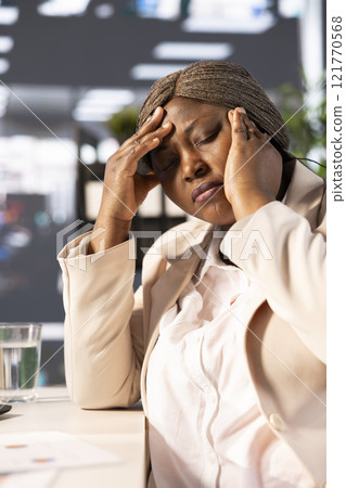 Office clerk having headache from stress while looking through financial business documents over accounting figures. Tired worker in pain, feeling discomfort, working late, suffering sleep deprivation Office clerk having headache from stress while looking through financial business documents over accounting figures. Tired worker in pain, feeling discomfort, working late, suffering sleep deprivation 121770568