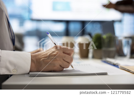 Financial consultant takes notes during a project briefing meeting, working on allocating available resources to meet the business objectives. Expert making future projections. Close up. 121770582