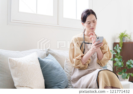 看智慧型手機的家庭主婦婦女人 看智慧型手機的家庭主婦婦女人 121771432