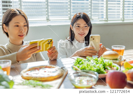 一位女士在餐桌上拍攝食物照片 121772654