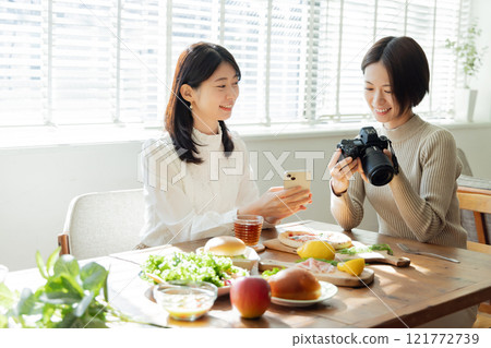 A woman taking a photo of food on the dining table 121772739
