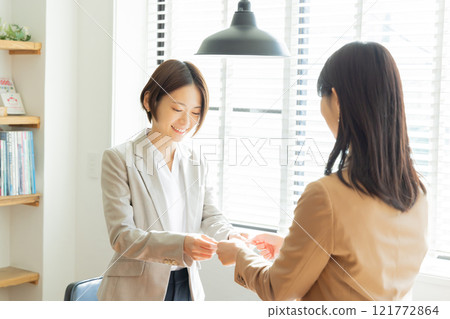 Women in casual clothes exchanging business cards Women in casual clothes exchanging business cards 121772864