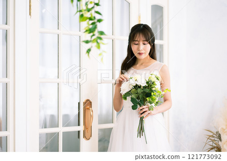 A young woman with long black hair wearing a wedding dress 121773092