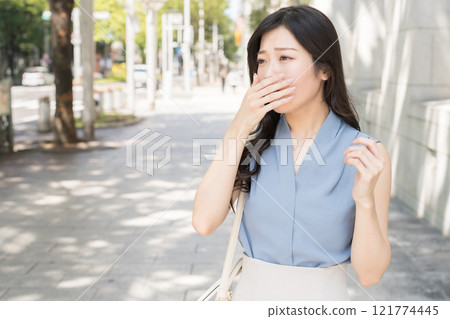 A sleepy businesswoman yawning in an office district 121774445