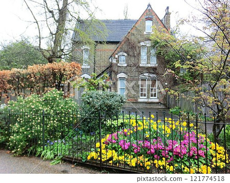 A country cottage-style home surrounded by beautiful flowers A country cottage-style home surrounded by beautiful flowers 121774518
