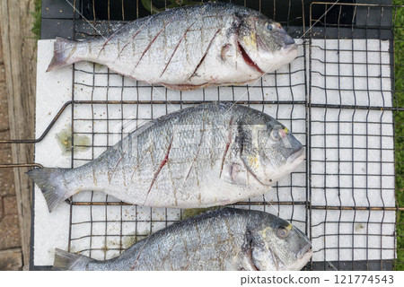 cooking sea fish. Raw dorado fish with spices on bbq mesh. cooking sea fish. Raw dorado fish with spices on bbq mesh. 121774543
