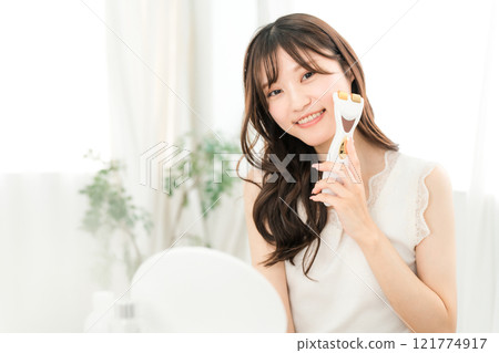 Young Asian woman massaging with a facial beauty device (skin care, lift up) 121774917