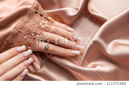 Female hands with pink nail design on silk and lace background Female hands with pink nail design on silk and lace background 121775468