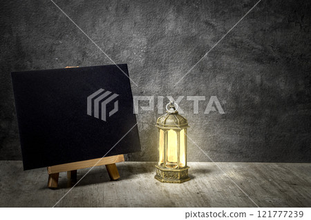 Wooden easel and card with Arabic lanterns on the desk with black background 121777239