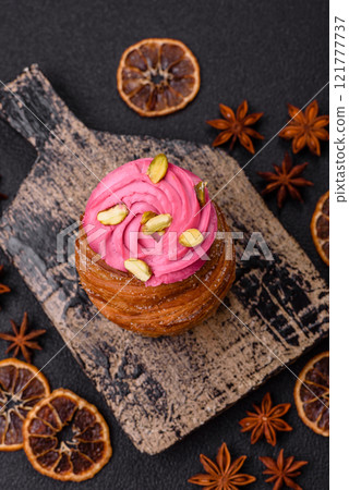 Sweet craffin or panettone garnished with raspberry and pistachio flavored cream 121777737