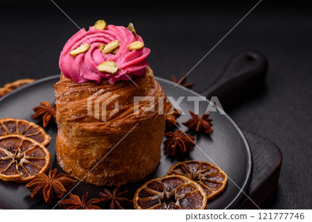 Sweet craffin or panettone garnished with raspberry and pistachio flavored cream 121777746