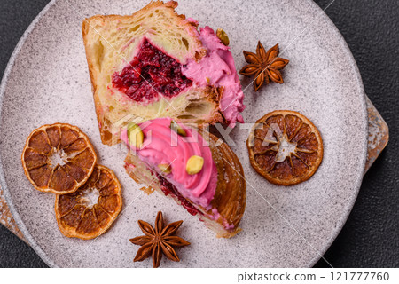 Sweet craffin or panettone garnished with raspberry and pistachio flavored cream Sweet craffin or panettone garnished with raspberry and pistachio flavored cream 121777760
